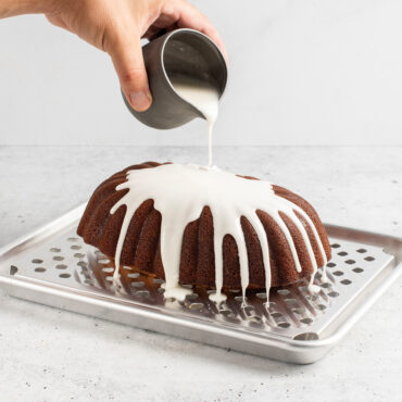 Quarter Sheet & Multi Task Rack with loaf cake, hand drizzling frosting over cake