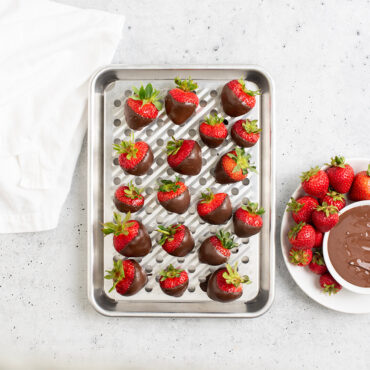 Overhead image of Quarter Sheet & Multi Task Rack with chocolate dipped strawberries, plate of strawberries and dish of chocolate next to pan