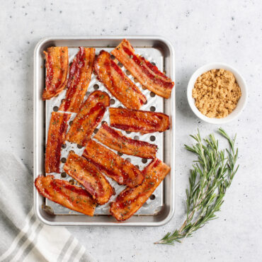 Overhead image of  Quarter Sheet & Multi Task Rack with bacon, small dish of brown sugar next to pan