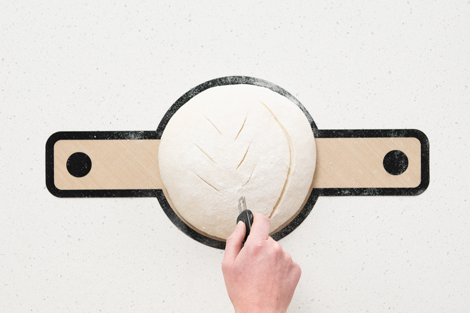 Retractable Bread Lame scoring a loaf of sourdough dough on the Silicone Lifting Sling