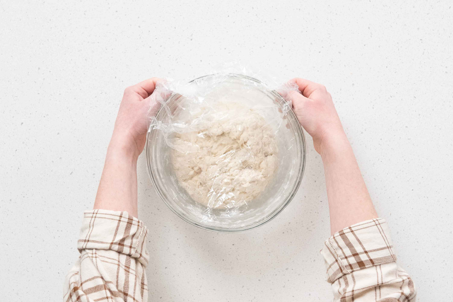 Covering a bowl of sourdough bread dough with a clear shower cap.