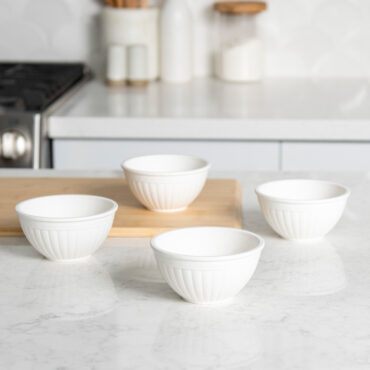 Four white mini bowls arranged separately on white countertop