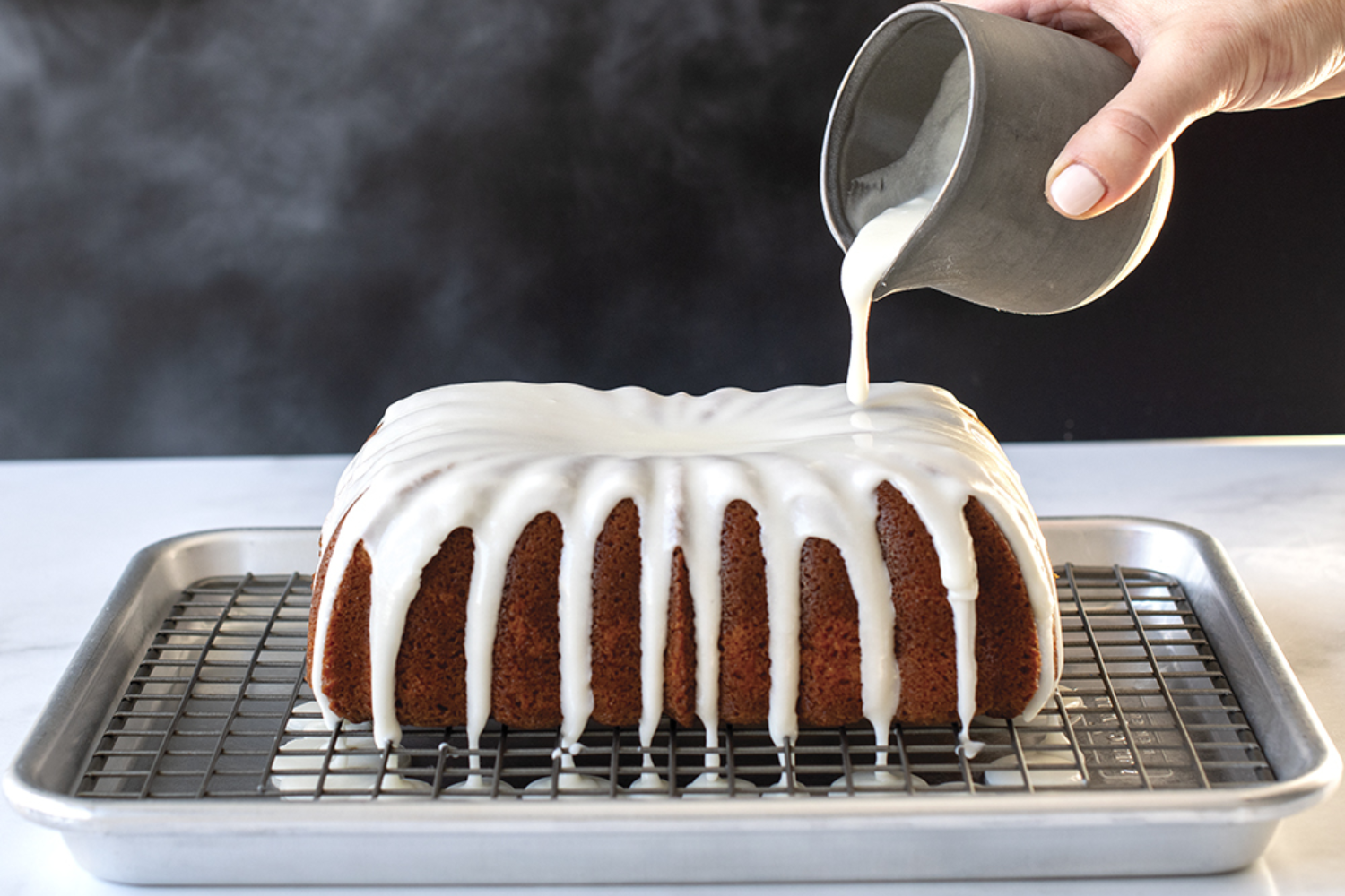 Naturals® Quarter Sheet Pan with Oven-Safe Nonstick Grid with a cake being glazed on top.