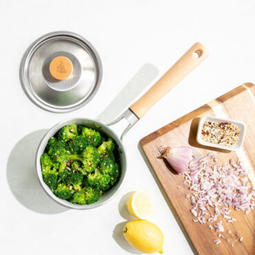 cardamom 1.5qt saucepan on with broccoli, lid next to it with cutting board of ingredients