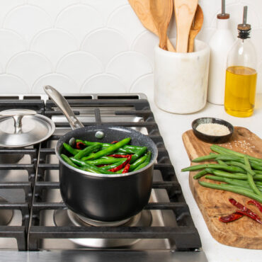 basalt 1.5qt saucepan filled with string beans on stovetop, lid placed behind pan and cutting board with ingredients next to stove on countertop