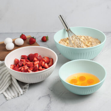 Nordic Ware 3 piece seaglass and white 5 quart, 3.5 quart and 2 quart bowls filled with dough, egg yolks, and strawberries