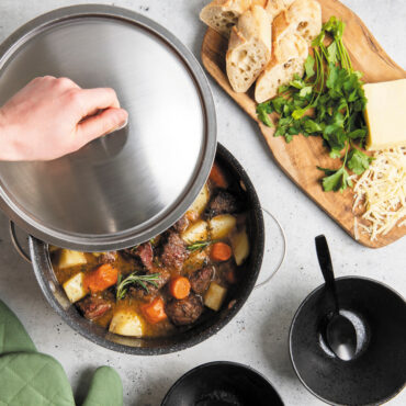 nordic ware 6 qt aluminum dutch oven with stew; hand holding lid by the knob