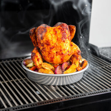 roasted chicken on vertical chicken roaster and veggies on outdoor grill
