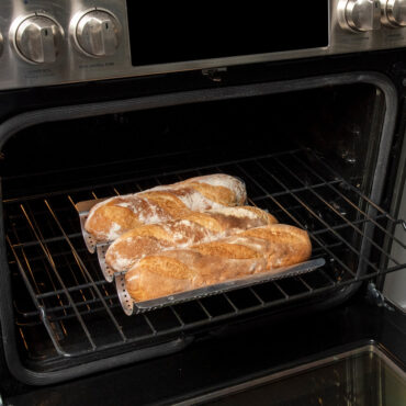Nordic Ware baguette & french bread pan staged in open oven with fresh baked baguettes