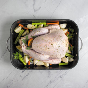 uncooked turkey and veggies prepped inside Nordic Ware Verde Grand Roaster with speckled nonstick interior and stainless steel handles