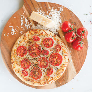 Round aluminum pizza crisper pan with perforated bottom, natural silver finish, showing airflow holes for crispy crusts